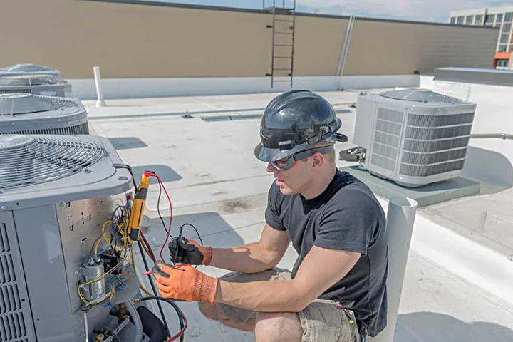 Emergency HVAC technician repairing rooftop cooling equipment