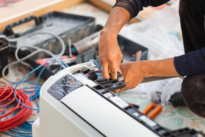Technician installing and wiring modern residential HVAC equipment